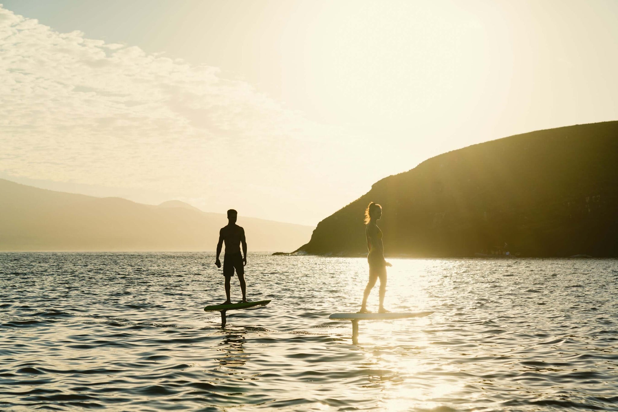 what is eFoil surfing - two people flying above waves on eFoils at sunset